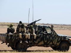 Security Escort for Solo Travel A military convoy security escort with armed soldiers on a camouflage-painted pickup truck in a desert landscape.